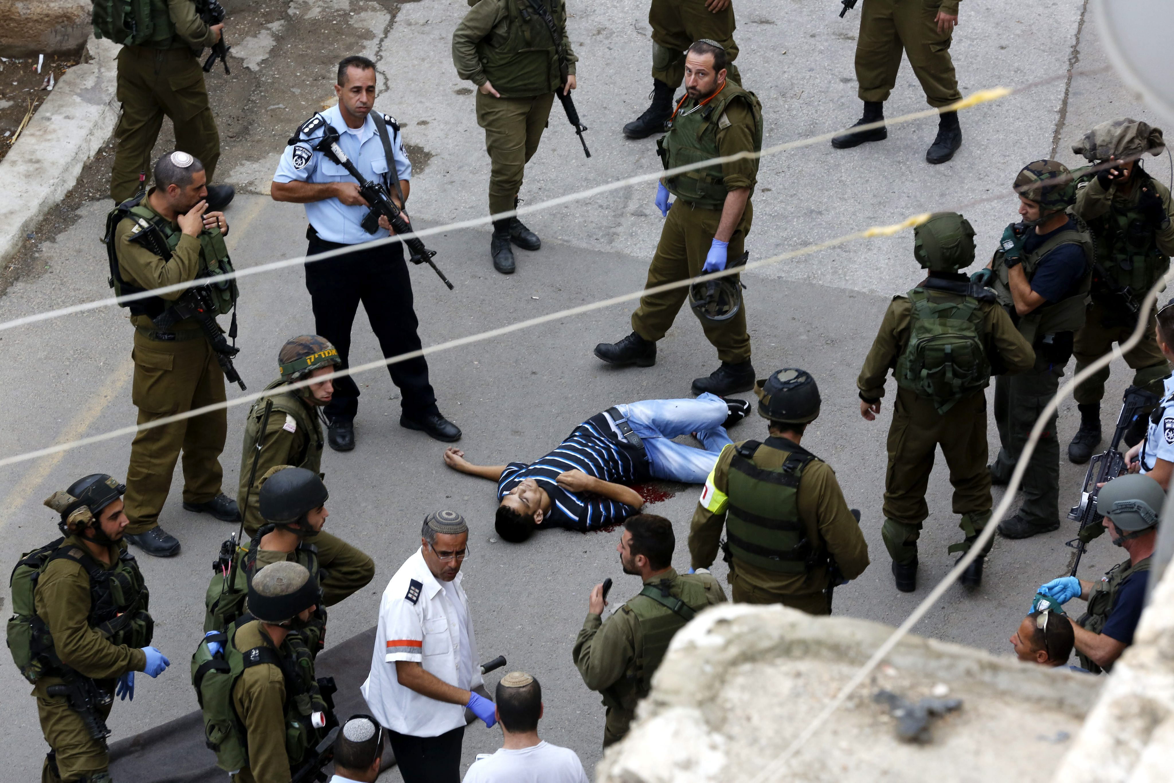 Soldados israelíes permanecen junto al palestino Said al Atrash, tras el ataque que tuvo lugar ayer junto a la Cueva de los Patriarcas en Cisjordania, cerca de Hebrón en el que, según la policía israelí, este intentó apuñalar a un agente de seguridad/EFE.